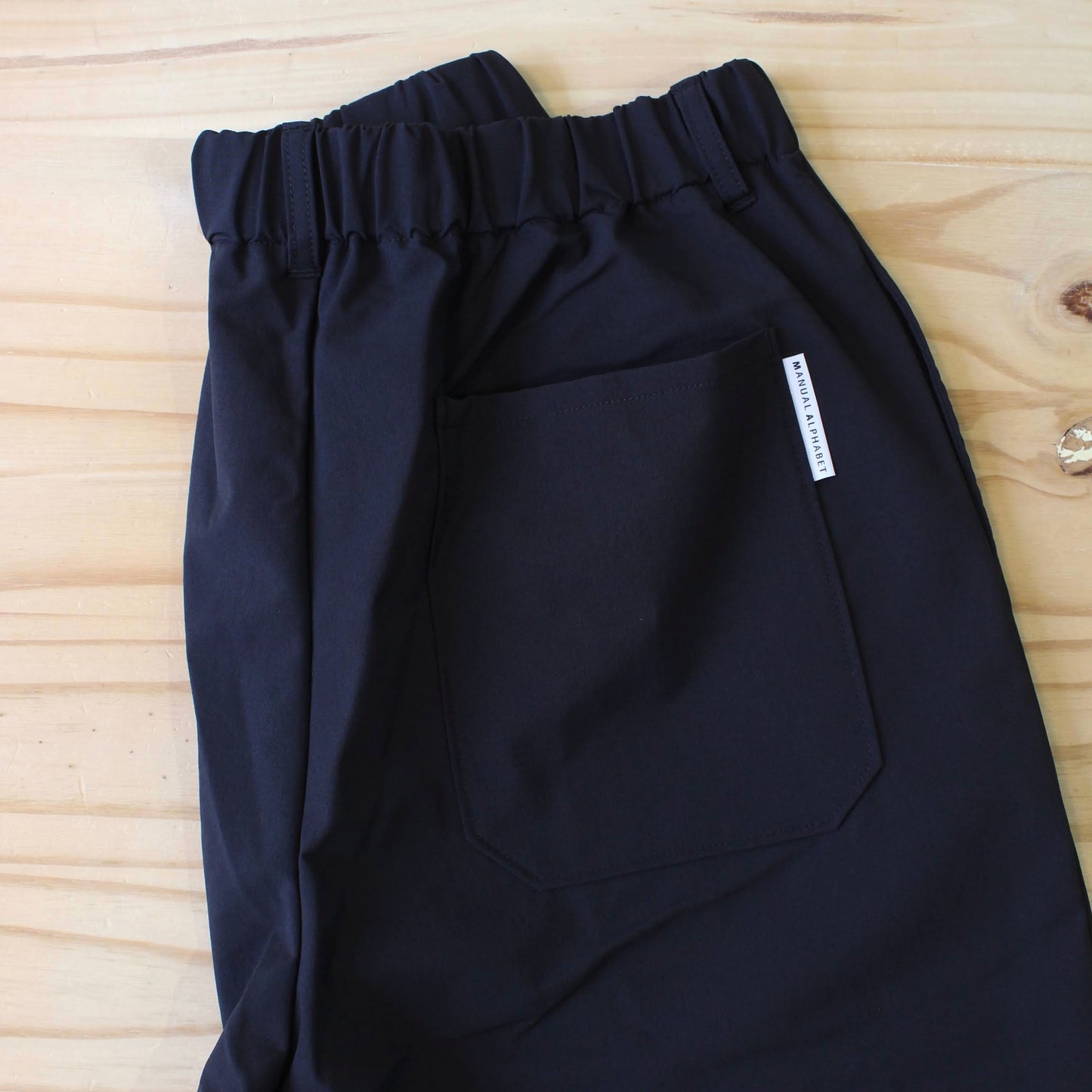MANUAL ALPHABET -
4WAY NYLON EASY TAPERED PANTS